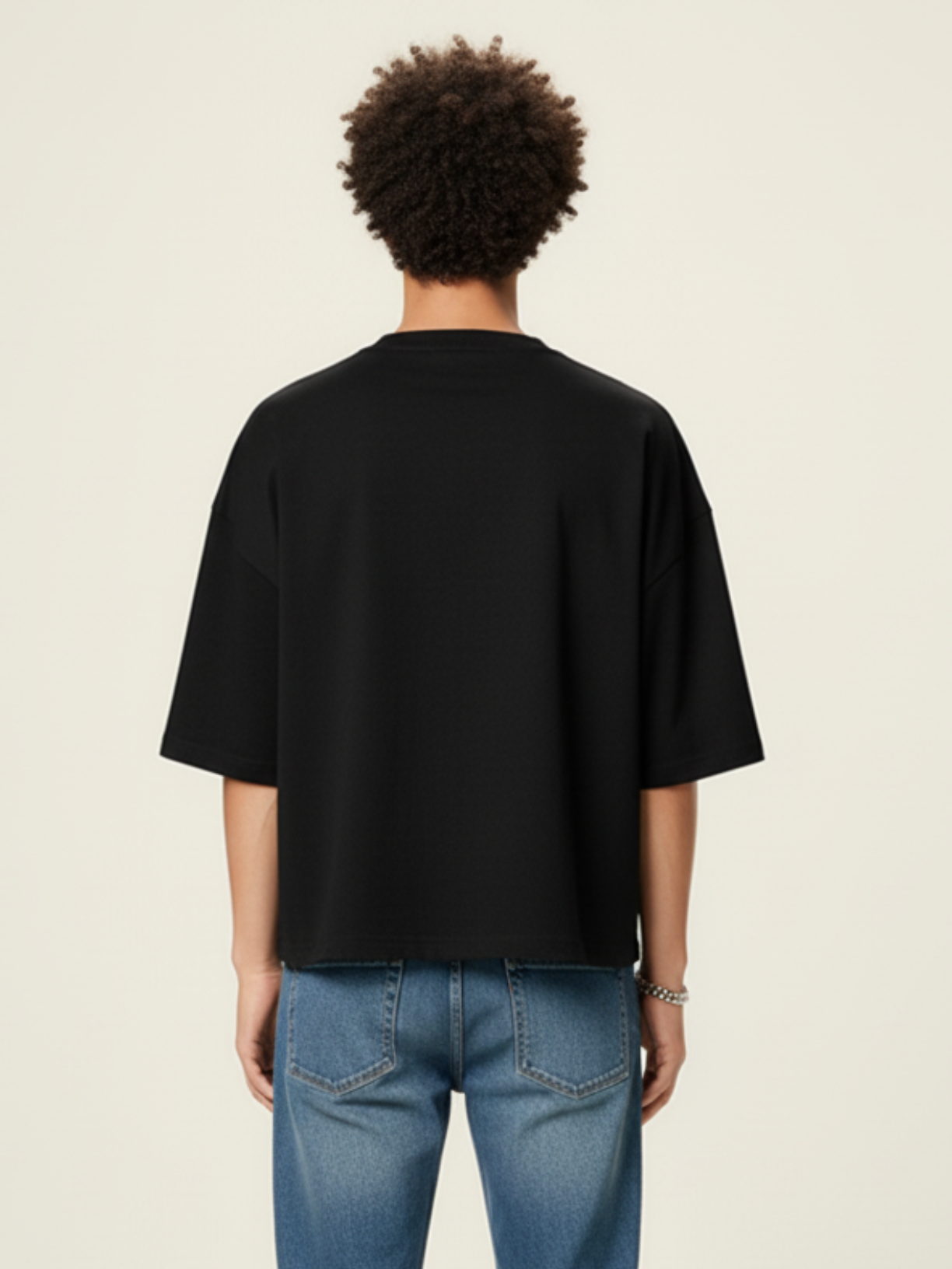 Person wearing a black t-shirt and blue jeans on a beige background