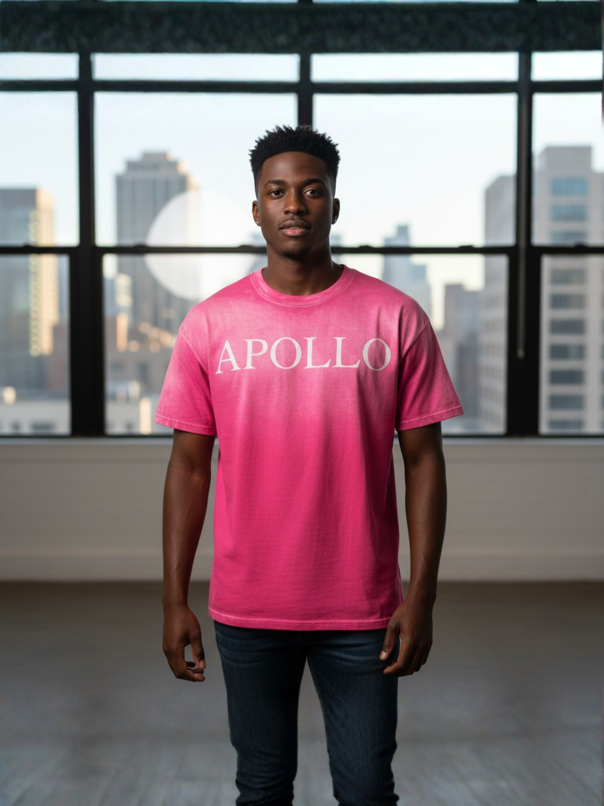 Person wearing a pink 'APOLLO' t-shirt in an indoor setting with large windows.