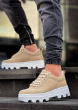 Beige sneakers with white soles worn by a person on steps.