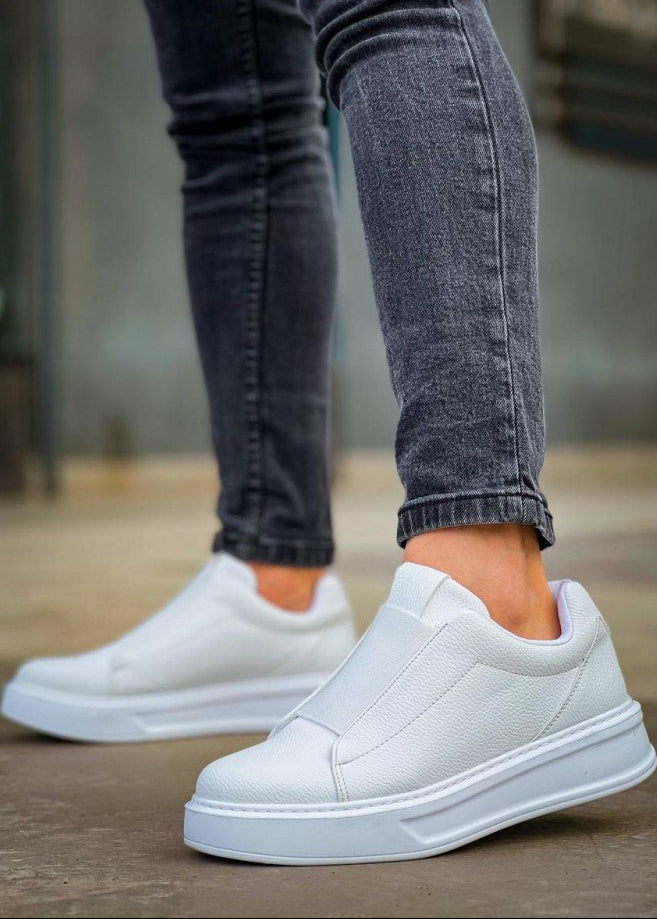 White slip-on sneakers worn with gray jeans on a blurred background