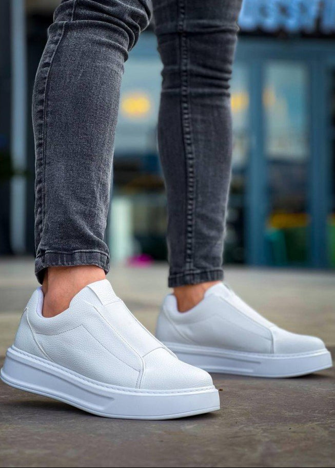 White slip-on sneakers worn with gray jeans on a blurred background