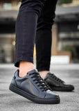 Black leather sneakers worn on a blurred outdoor background