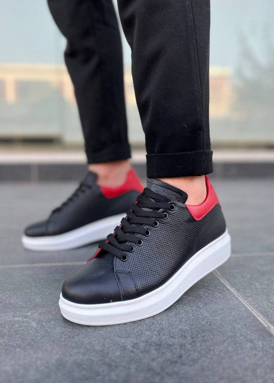 Black sneakers with white soles worn on a tiled floor