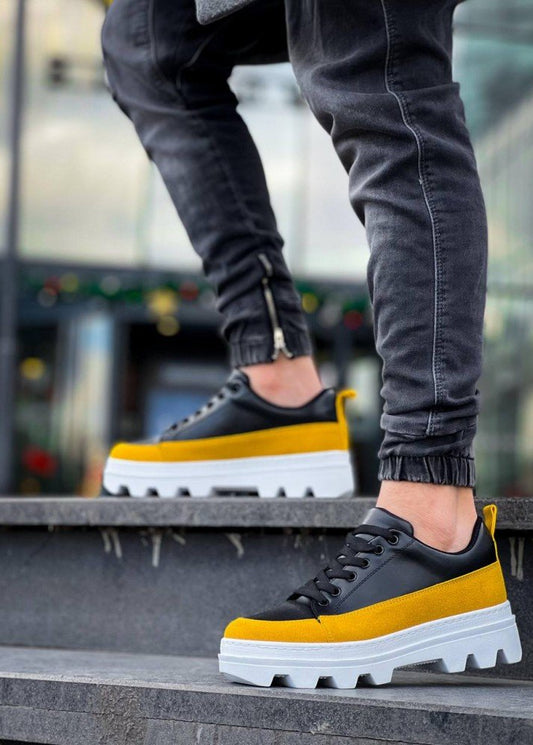 Black and yellow sneakers with white soles worn by a person on steps.