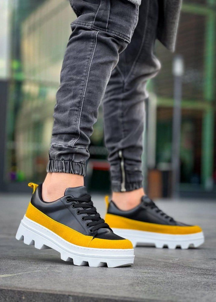 Black and yellow sneakers with white soles worn by a person on a blurred background
