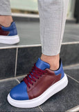 Person wearing maroon and blue sneakers on a stone floor.