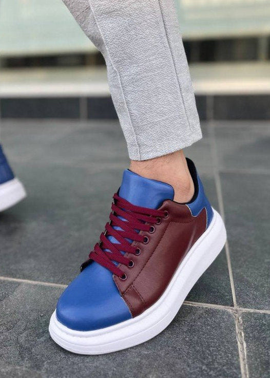 Blue and brown sneakers with white soles worn on a tiled floor.