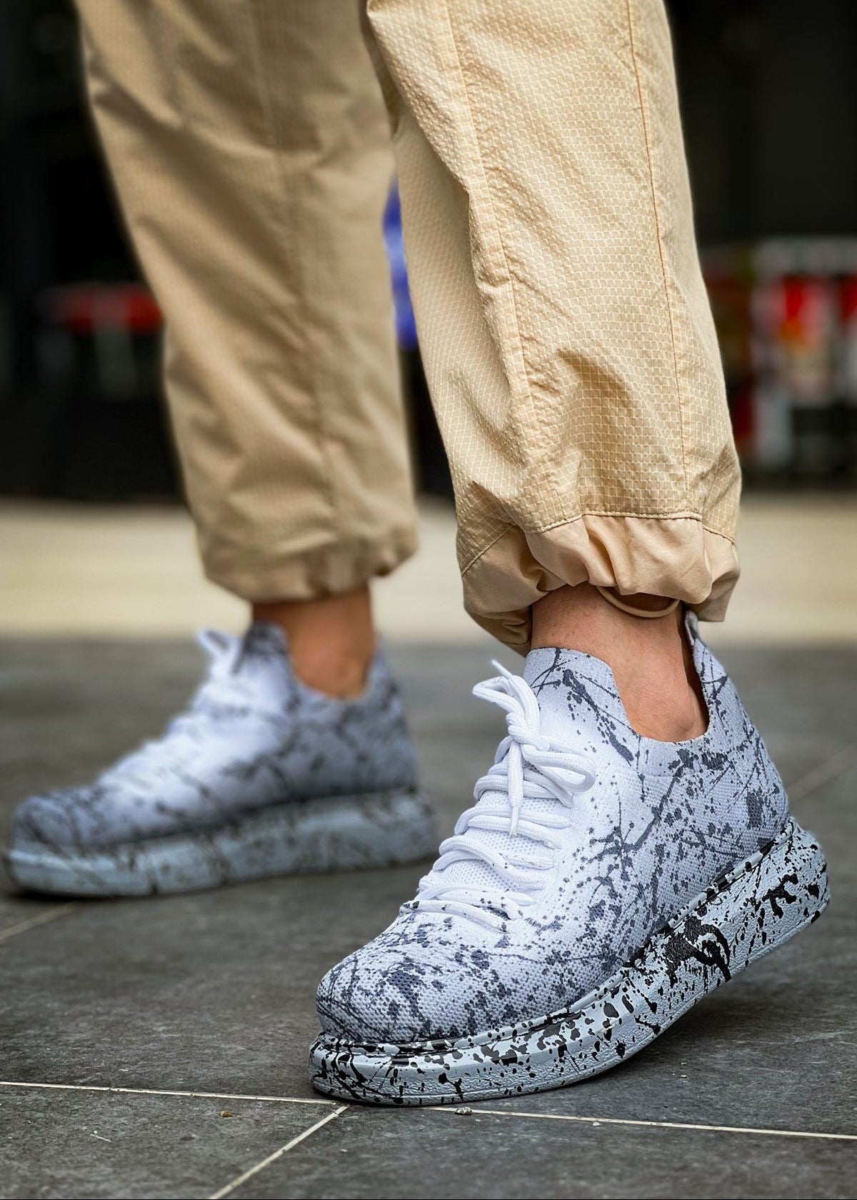 A pair of grey sneakers with black mesh design and white laces on a person's foot, showcasing the side profile of the shoes.