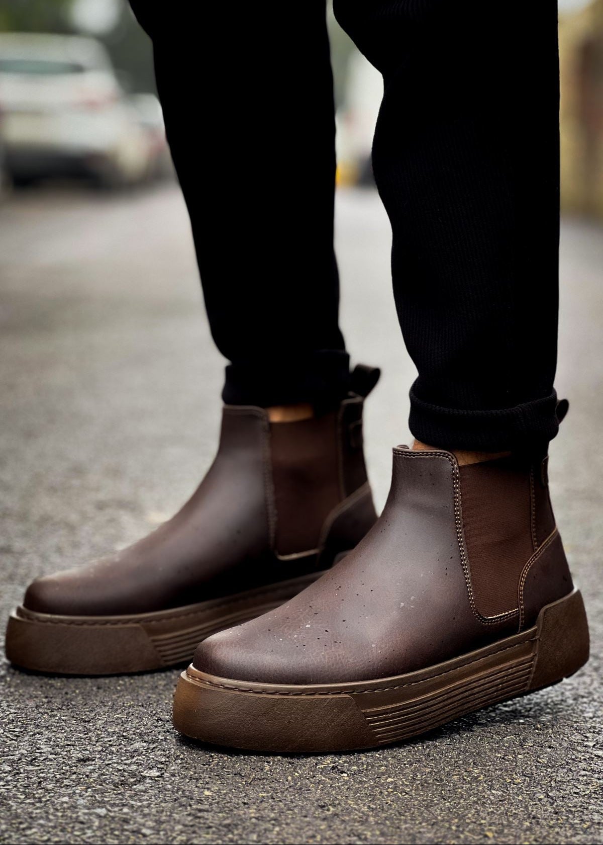 Close-up of Avalon Coffee Brown Chelsea boots worn outdoors on wet pavement.