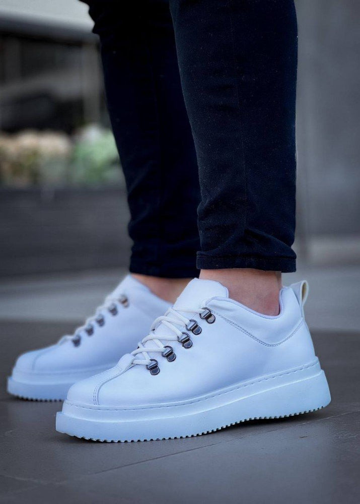 White sneakers worn with dark jeans on a blurred background